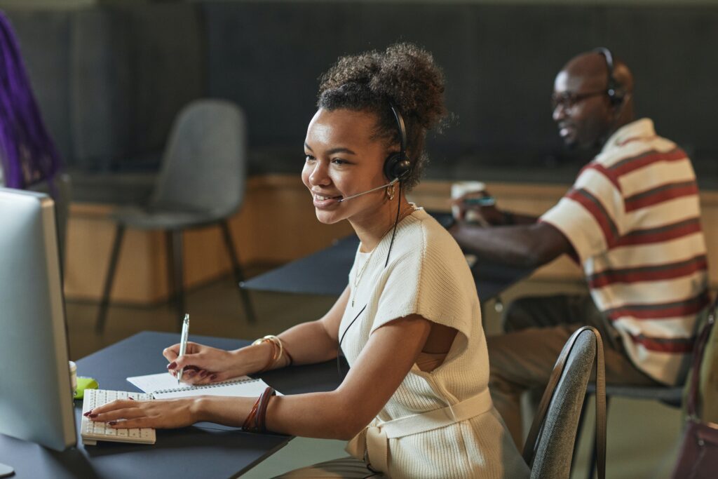 a person wearing headphones and writing a customer a feedback on a notebook
