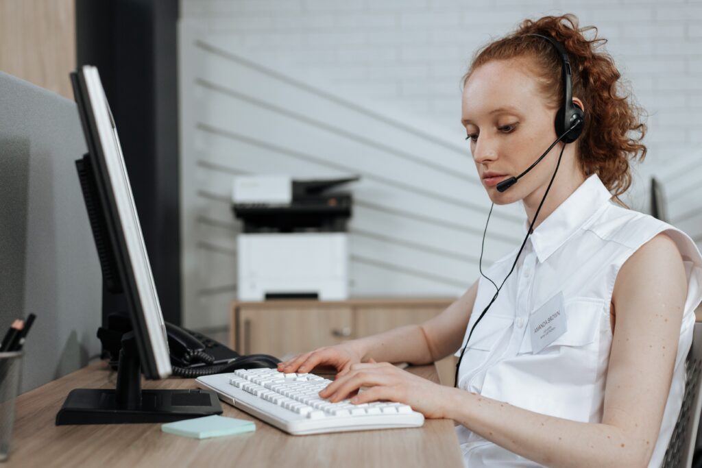 a woman wearing a headset and typing on a keyboard about Customer Service Context