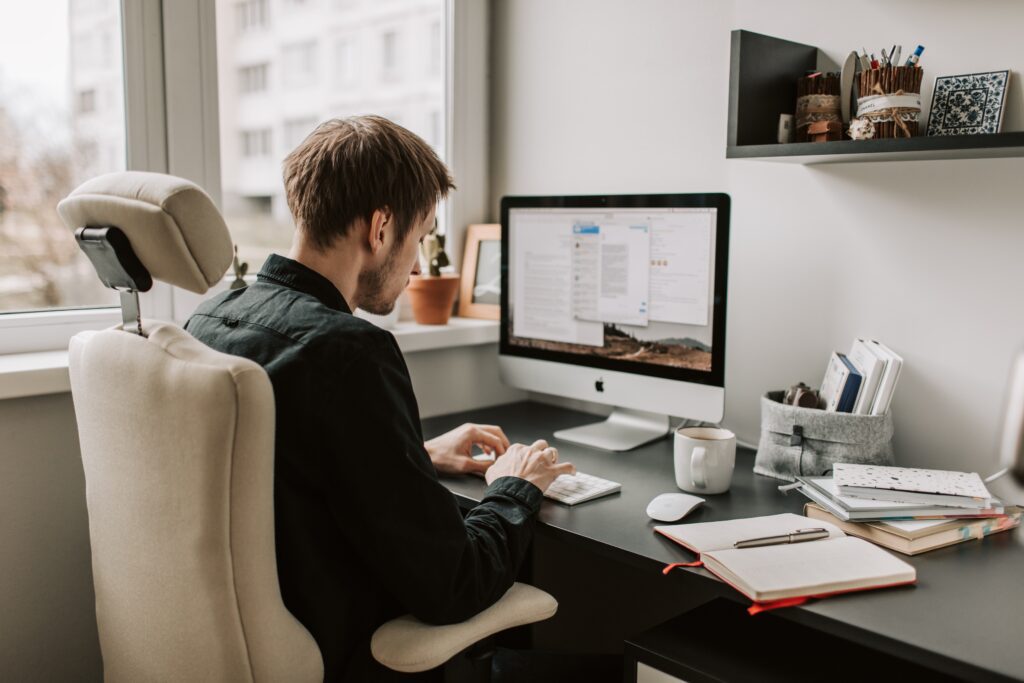 a man wearing a black long sleeves sitting at a desk using a computer working as a Virtual Assistant