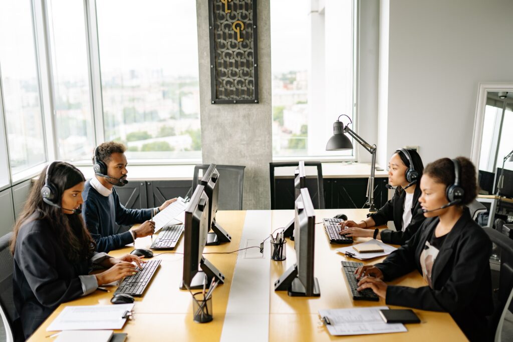 a group of people working at computers discussing de-escalation techniques customer support