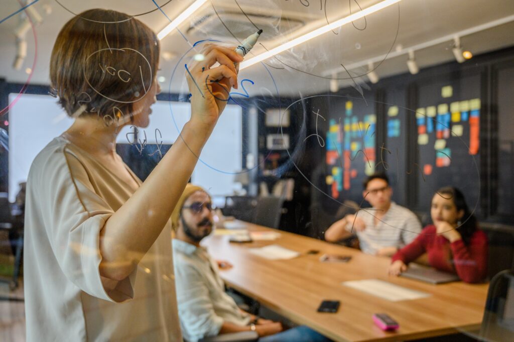 a woman team leader writing on glass board having a discussion about Offshoring Philippines