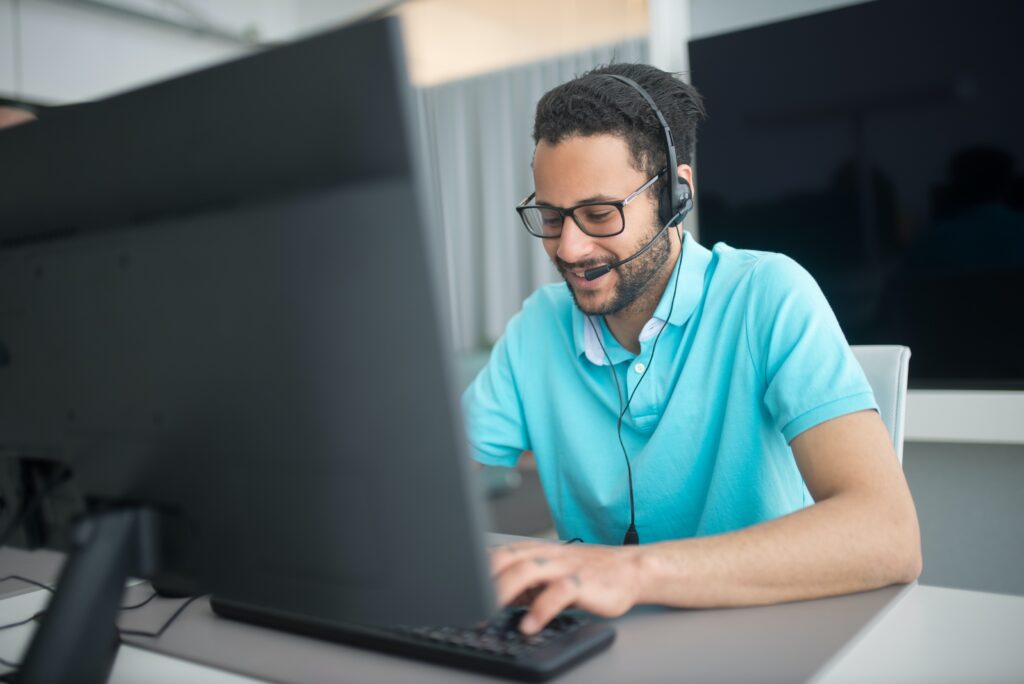 a man wearing headphones and using a computer searching on what Is Automated Customer Service.