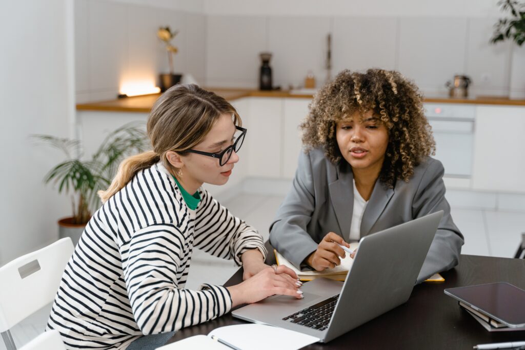 a couple of women sitting at a table looking at a laptop content moderation best practices