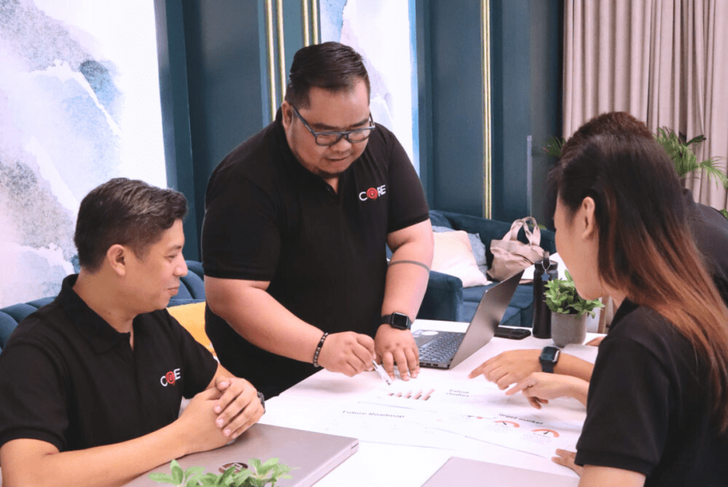 Three individuals in black shirts collaborating on a laptop. Managed services involve outsourcing services for improved efficiency.