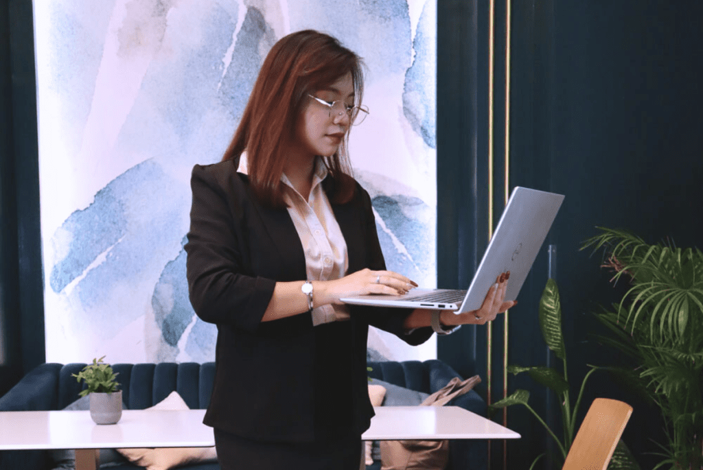 A businesswoman in a suit working on a laptop, representing outsourcing payroll pros and cons.