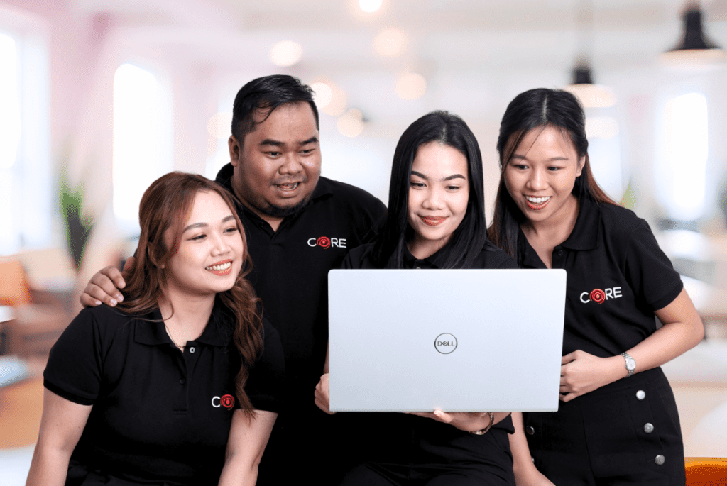 Three individuals in black shirts collaborating on a laptop for project management.