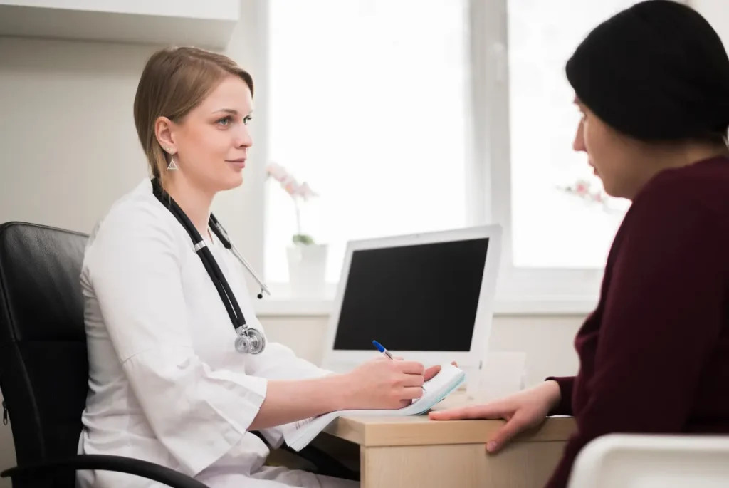 A female doctor discusses clinical trial options for a rare disease with a patient in a medical office setting.