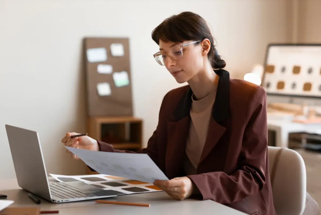 A woman in glasses focuses intently on her laptop, representing an outsourced bookkeeper at work.