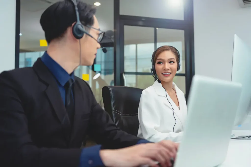 Asian businesswoman and man collaborating in a call center, showcasing their customer service skills effectively.