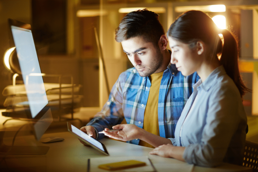 A man and woman examining a tablet, discussing AI applications in digital advertising.