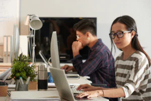 A woman wearing glasses is focused on her laptop, representing remote work in the outsourcing industry in the Philippines.