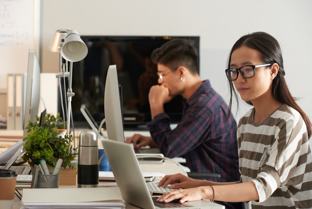 A woman wearing glasses is focused on her laptop, representing remote work in the outsourcing industry in the Philippines.