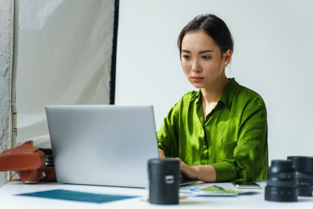 A woman in a green shirt sits at a desk with a laptop, representing hybrid work in the Philippines.