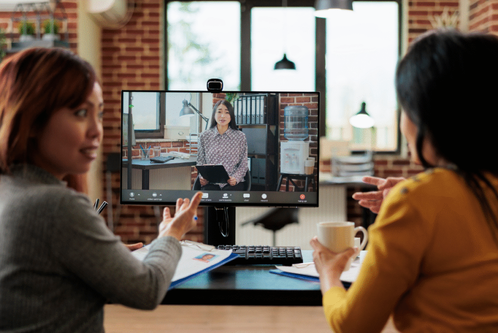 Two women engaged in discussion at a table, focused on a computer screen, emphasizing strategies for retaining talent.