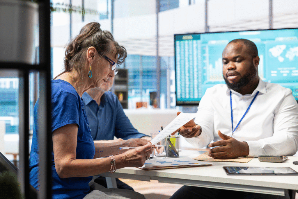 Three professionals collaborating at a table with a laptop, discussing business process outsourcing in healthcare.