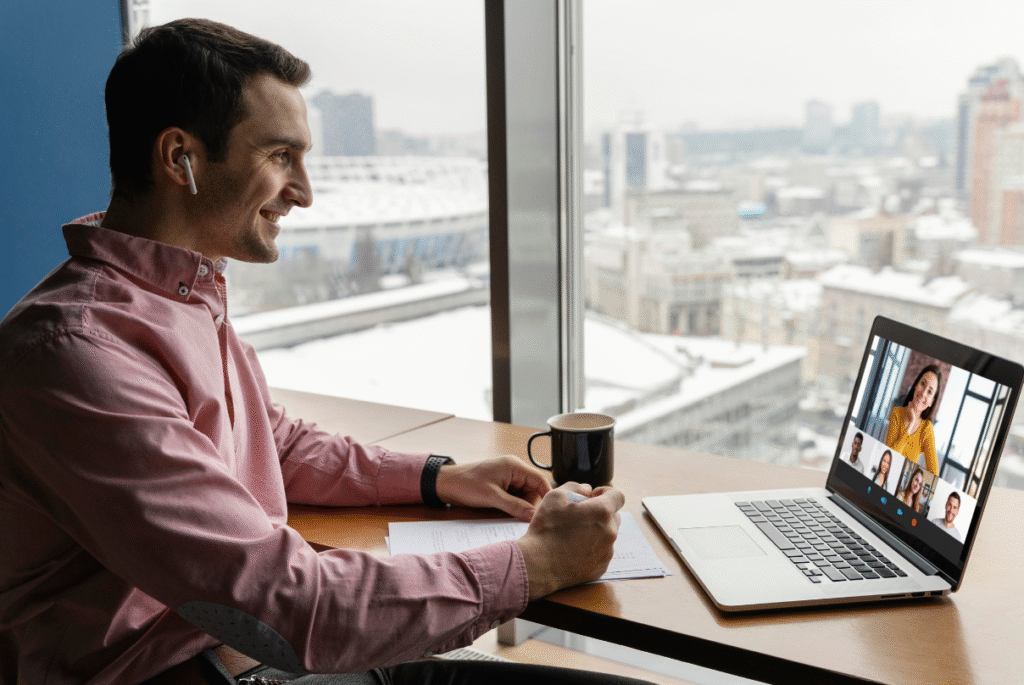 A man sitting at a desk with a laptop and camera, engaged in remote onboarding activities.