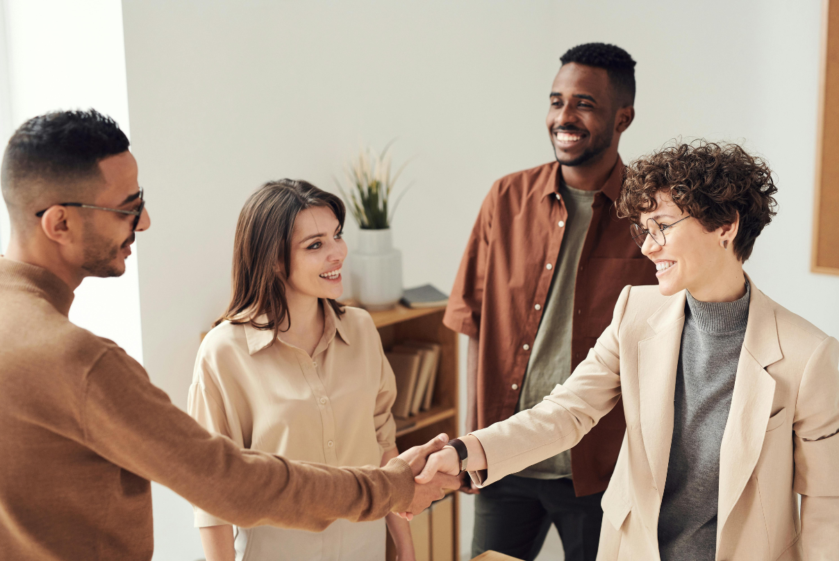 A group of professionals shaking hands in an office, symbolizing collaboration in employee retention strategies.