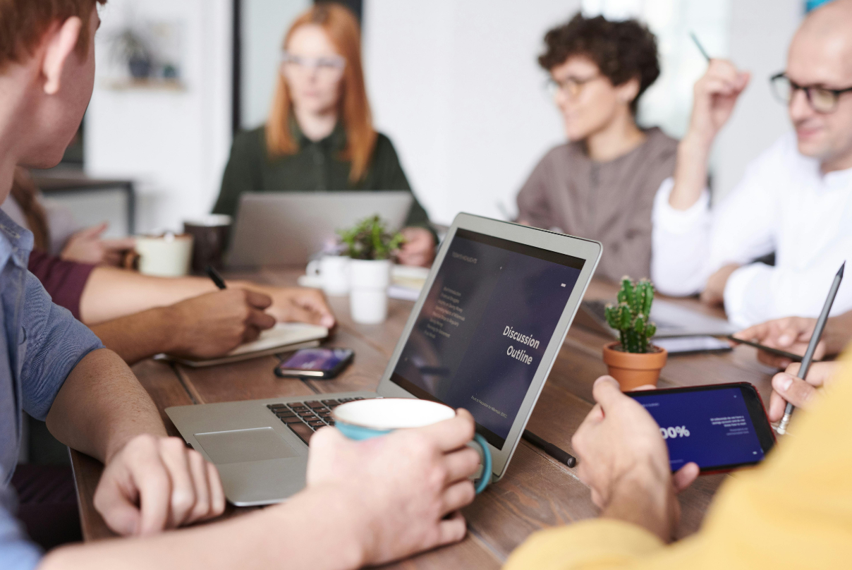A group of professionals from EOR companies collaborating around a table with laptops open in a modern office setting.