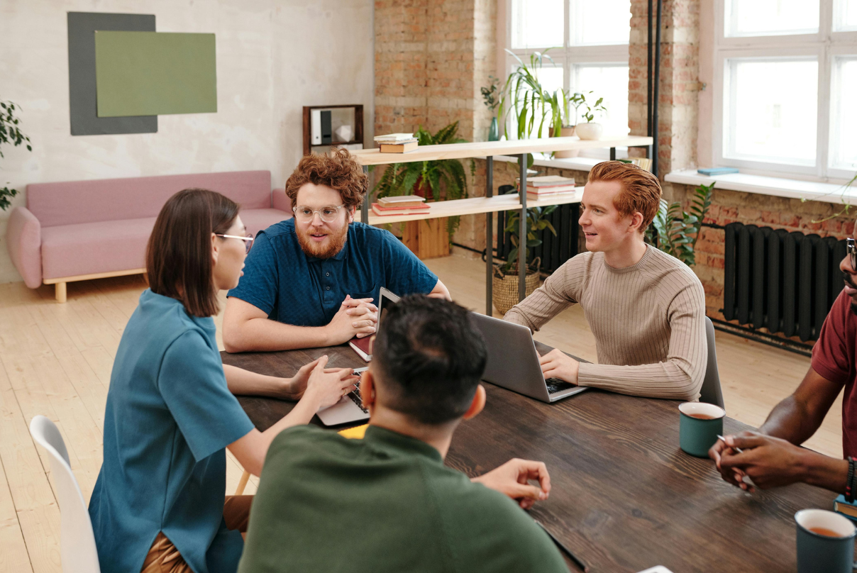 A group of professionals collaborating around a table in a modern IT-BPM office setting.