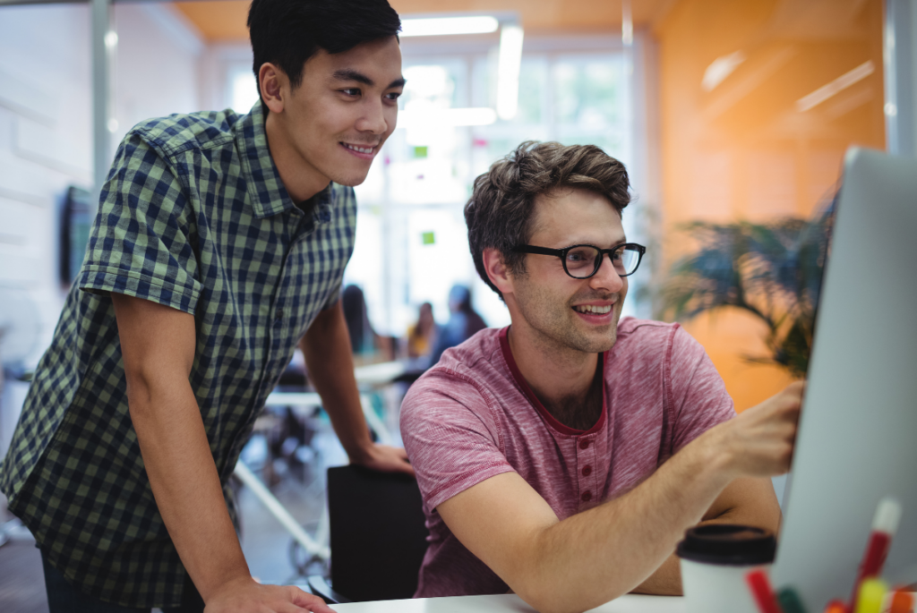 two male philippine employees  working looking at monitor screen